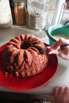 a bundt cake sitting on top of a red plate next to a bowl of cereal