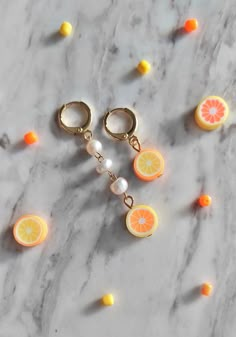 two oranges with pearls on them sitting on a marble surface next to other fruit