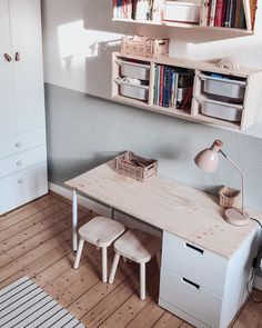 a desk with two stools in front of it and bookshelves above the desk