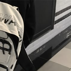 a white and black backpack sitting on top of a tiled floor next to a window