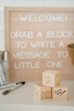 three wooden blocks sitting on top of a white table next to a pen and paper