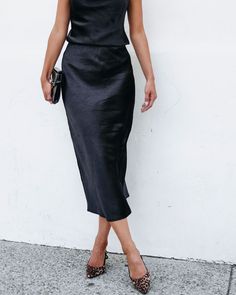 Perfect for any occasion, this black midi skirt combines comfort and style effortlessly! The Muse By Magnolia Black Satin Midi Skirt boasts an elastic waistband for a customizable fit and is made of 100% polyester for a luxurious feel. Style it with the matching satin cami along with some strappy heels and a matching clutch for an elevated workwear look! Black Satin Midi Skirt, Sorority Rush Outfits, Rush Outfits, Loungewear Dresses, Gameday Dress, Casual White Dress, Satin Midi Skirt, Game Dresses, Black Midi Skirt