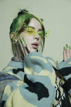 a woman with green hair and glasses on her face, wearing an oversize sweater