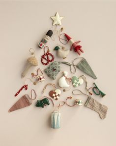 a small christmas tree made out of various items on a white surface with the shape of an ornament