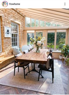 a wooden table sitting in the middle of a room with lots of windows on it