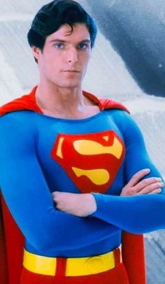 a man dressed as superman standing with his arms crossed