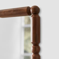 a close up of a wooden rail with a mirror in the backgrouund