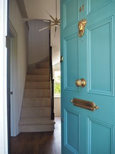 a blue door with a gold handle on it and a staircase leading up to the second floor