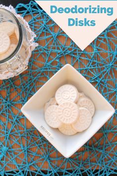 some cookies are sitting in a white bowl on a blue tablecloth and next to a glass jar