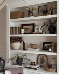 a white book shelf filled with books and vases