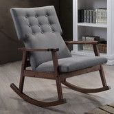 a rocking chair with grey upholstered fabric and wooden frame in front of a bookcase