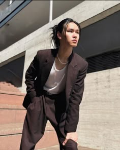 a woman standing in front of a building with her hand on her hip and looking off to the side