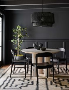 a dining room table with chairs and a potted plant in the center on a rug