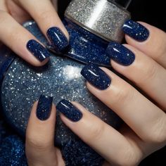 Transform your nails into a breathtaking canvas with our Starry Night nail art design. Begin with a deep, mesmerizing dark blue base, symbolizing the serene night sky. Gradually blend in hues of midnight blue and indigo, creating a seamless ombre effect. Add delicate silver sparkles, mimicking twinkling stars scattered across the vast expanse. Highlight with tiny white dots to represent distant galaxies. Seal the masterpiece with a glossy top coat, enhancing the celestial beauty. This design captures the enchanting allure of a starry night, perfect for adding a touch of cosmic elegance to your style Dark Nails With Glitter Accent, Navy Blue Nails With Gold Glitter, Dark Blue Nails With Moon And Stars, Dark Blue With Sparkles Nails, Dark Blue And Glitter Nails, Navy Blue Xmas Nails, Sparkling Blue Nails, Midnight Blue Christmas Nails, Ombre Dark Blue Nails