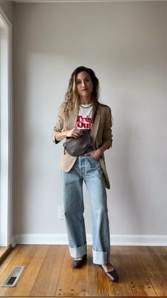 Casual chic spring outfit idea with a camel blazer, graphic tee, baggy cuffed jeans, and ballet flats Blazer Outfit With Jeans, Work Bag Outfit, Slouchy Tapered Jeans Outfit, Graphic Tee Winter Outfit, Baggy Cuffed Jeans Outfit, Baggy Blazer Outfit, Baggy Jeans And Blazer Outfit, Graphic Tee And Jeans, Rolled Jeans Outfit