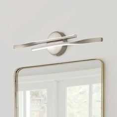 a bathroom mirror sitting on top of a white wall next to a sink and window