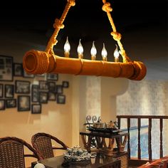 a wooden chandelier hanging from the ceiling over a dining room table with wicker chairs