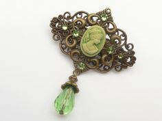 This small unique hair clip is a beautiful accessory for the vintage style. The hair clip is made of bronze metal. In the middle is a small cameo with lady in pearly green. the hair clip is also decorated with crystals in green. At the bottom of the hair clip is attached a pendant with a glass bead. The hair clip, including the drop pendant, measures 7 L x 5.5 W cm. Small Hair Clip, Festive Hair, Unique Hair Clip, Hair Accessories Vintage, Small Hair Clips, Accessories Vintage, Drop Pendant, Style Gift, Birthday Gifts For Her