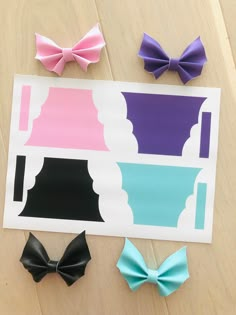 four different colored bow clips on top of a piece of paper next to each other