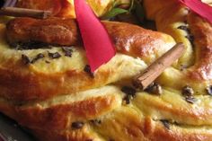 a close up of bread on a plate with red ribbon and cinnamon sticks sticking out of it