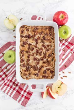 an apple pie with pecans and apples on the side, in a white baking dish