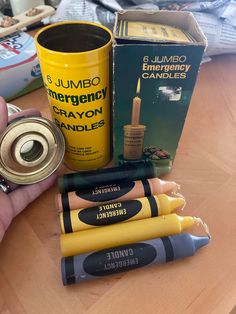 a hand holding a yellow cup next to several different types of items on a table