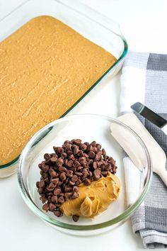 a glass bowl filled with chocolate chips next to a baking pan full of cake batter