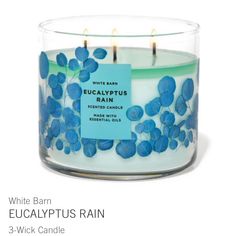 a white candle with blue flowers on it and a label that says eucalyptusplus rain