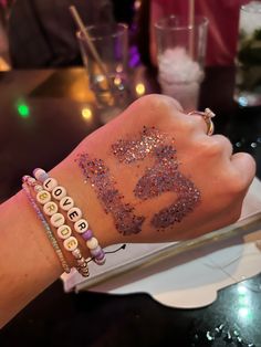 a woman's arm with bracelets and beads on it that have letters written in them