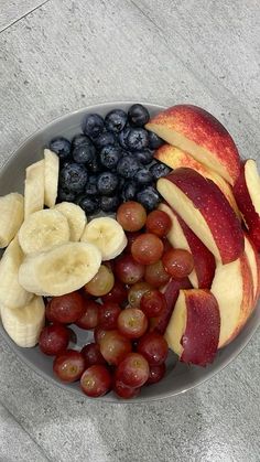 a plate with grapes, apples, and bananas on top of it next to a banana