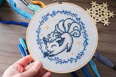 someone is holding up a cross stitch hoop