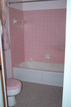 a bathroom with pink tiles on the walls and floor, including a toilet and bathtub