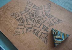 an ornament is laying on top of a piece of cardboard with blue and brown designs