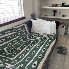 a bed with a green and white bedspread sitting on top of a wooden floor