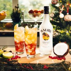 two glasses filled with ice next to a bottle of malbu bay breeze on a table