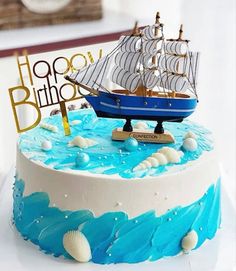 a blue and white cake with a sailboat on it's side that says happy birthday