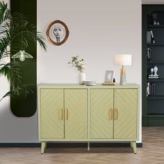 a living room with green furniture and a potted plant on the sideboard in front of it