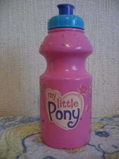 a pink water bottle with the words my little pony on it sitting on a bed