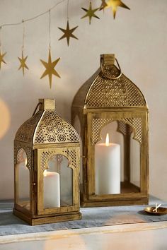 two lit candles sitting on top of a table next to a star shaped light fixture