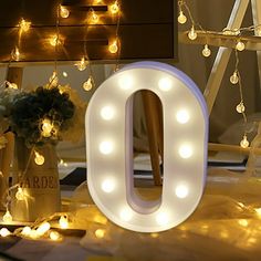 the letters o are lit up with fairy lights and flowers in vases on the floor