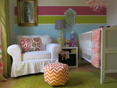 a baby's room decorated in pink, green and yellow with a crib