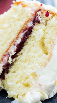 a piece of cake with white frosting and berries on top sitting on a plate