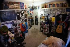 a room filled with lots of posters and pictures on the wall next to a bed