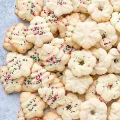 a pile of white cookies with sprinkles on top and one cookie in the middle