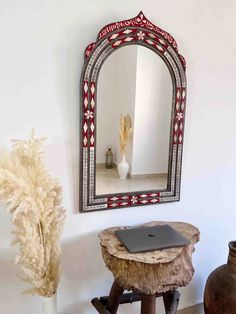 a laptop computer sitting on top of a wooden stool in front of a large mirror