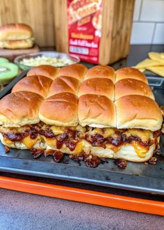 a large sandwich sitting on top of a pan next to some pickles and cheese