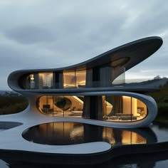 an unusual house is lit up at night with the lights on and reflecting in the water