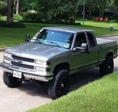 the truck is parked on the side of the road in front of some grass and trees