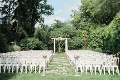 an outdoor ceremony setup with white chairs and flowers