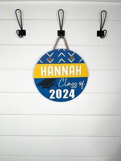 a blue and yellow sign hanging from hooks on a wall with the name hannah class of 202